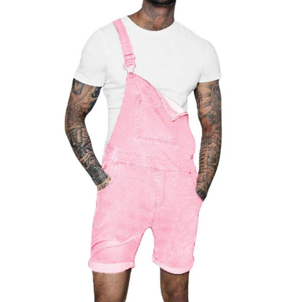Front view of a tattooed model wearing pink denim short overalls over a white T-shirt