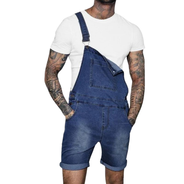 Front view of a tattooed person wearing dark denim bib shorts with one strap fastened and pockets