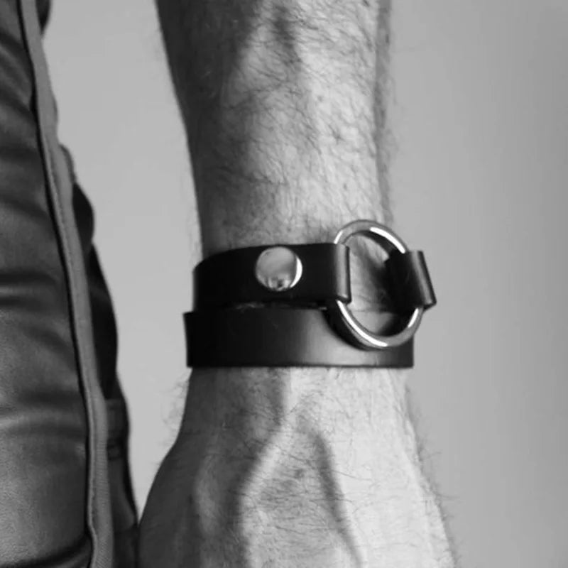 Close-up black leather bicep bracelet with a silver ring clasp on a hairy arm