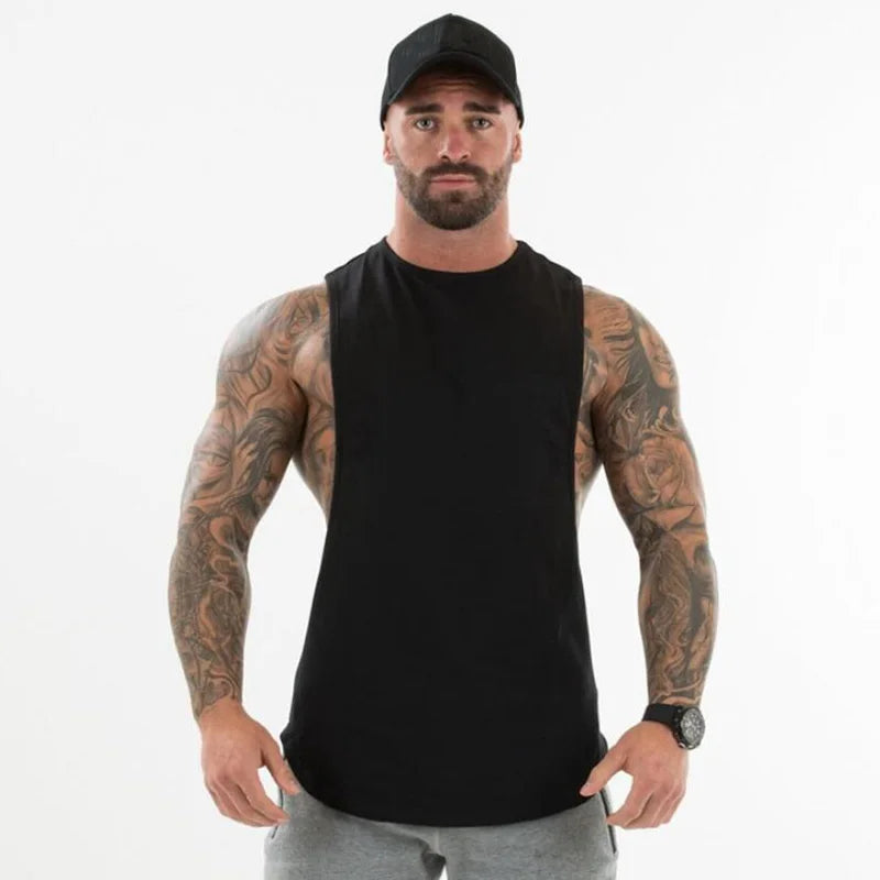 Front-facing bearded person wearing a black sleeveless muscle tank and gray sweatpants