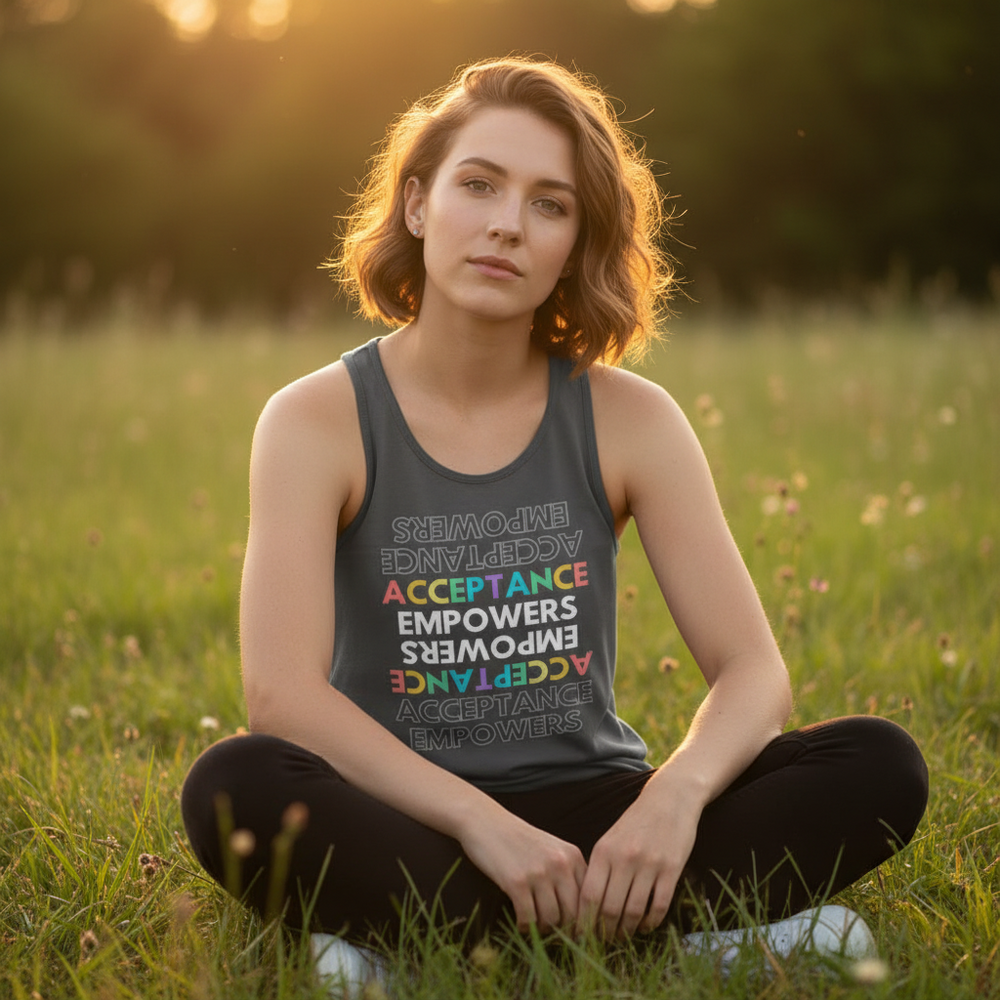 Acceptance Empowers Unisex Tank Top with "Acceptance Empowers" in rainbow colors, worn by a queer femme in sunset grass.