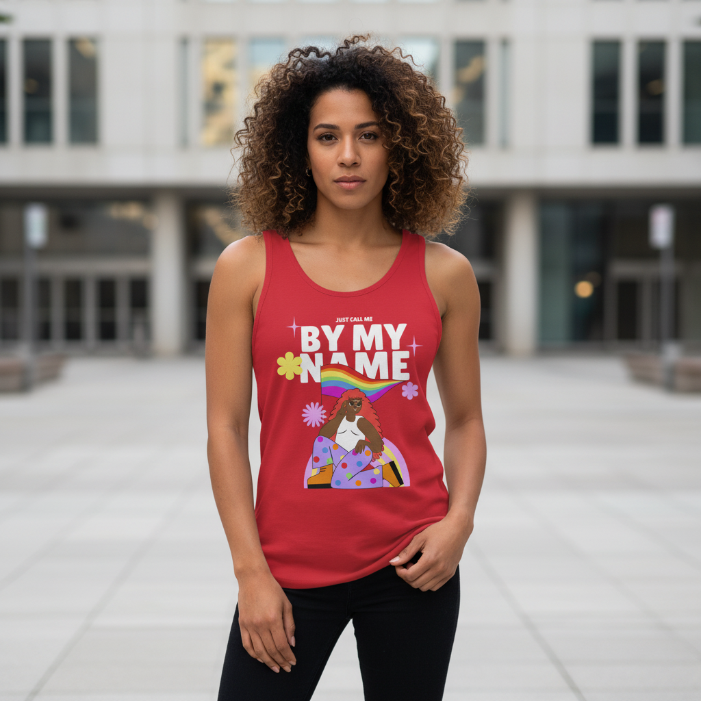 Unisex tank top with vibrant “BY MY NAME” text, a femme figure, florals, and rainbow; worn outdoors by a curly-haired woman.