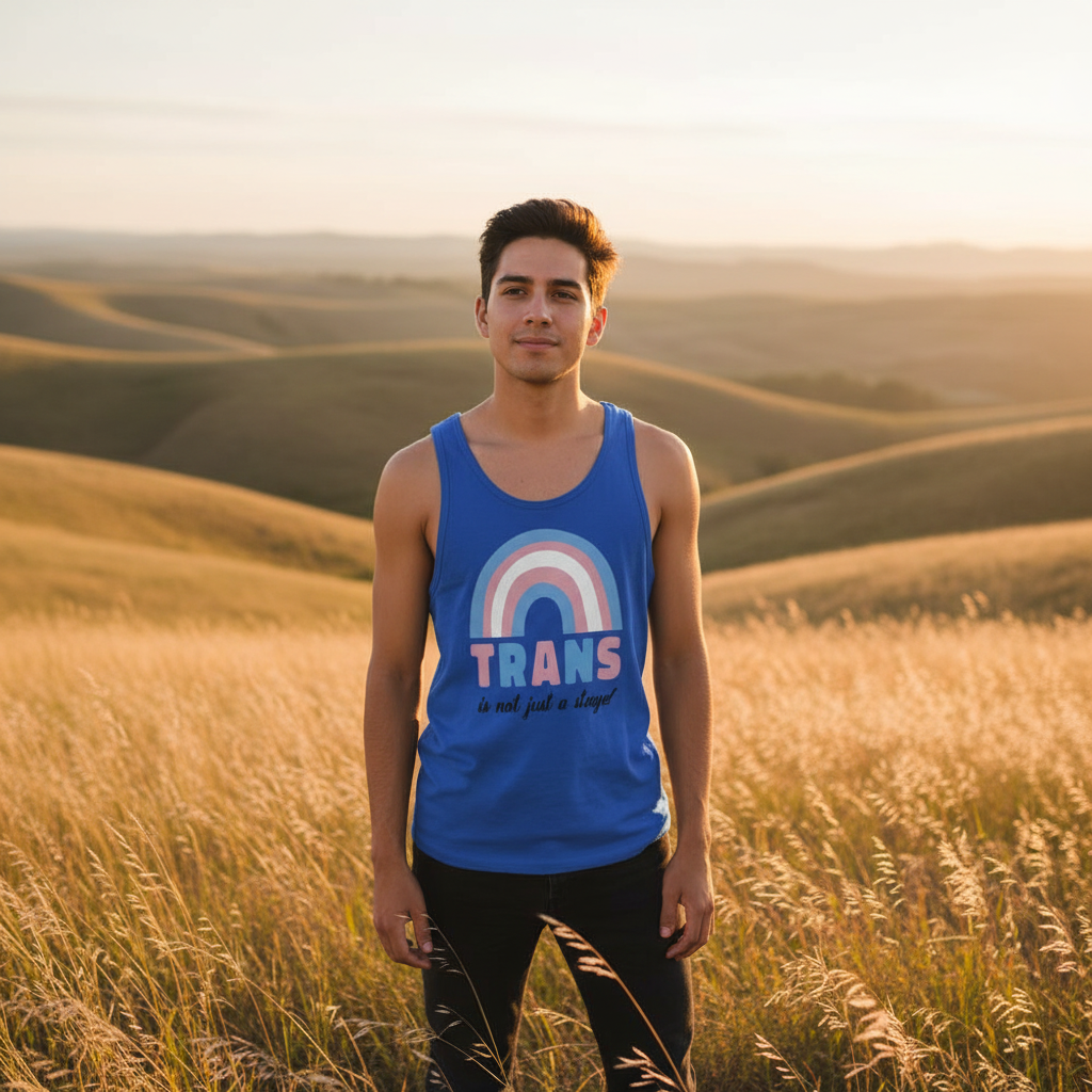 Young person in a grassy field at golden hour, wearing the Trans Is Not Just A Stage! Unisex Tank Top featuring a pastel rainbow graphic and TRANS text, embodying empowerment and queer pride.