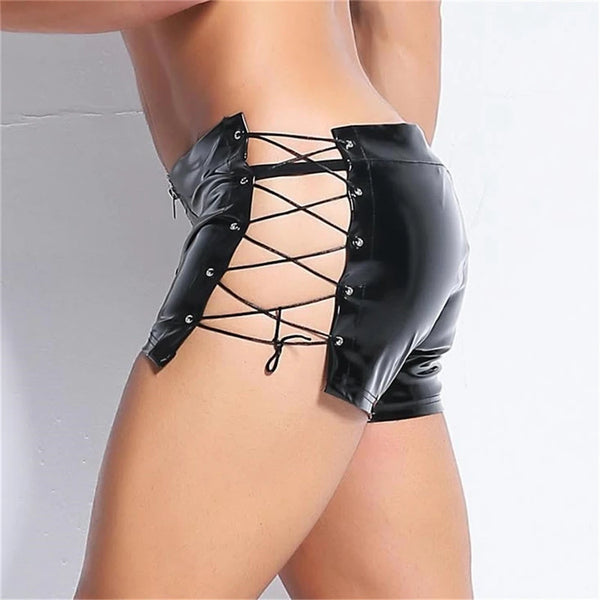Rear three-quarter close-up of a model wearing black faux-leather shorts with lace-up sides