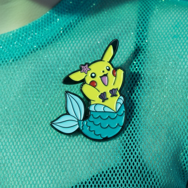 Close-up of a mermaid Pikachu enamel pin on shimmering turquoise mesh fabric