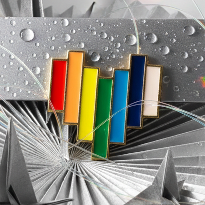 Rainbow heart enamel pin with vertical colored bars on a geometric silver background