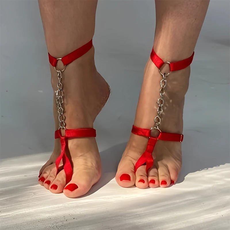 Close-up of feet wearing red satin ankle straps linked to thigh chains