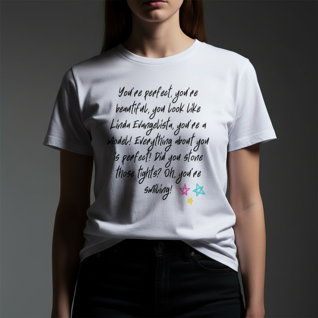 Unisex pride T-shirt with handwritten black text "You Look Like Linda Evangelista" and rainbow star doodles along the bottom.