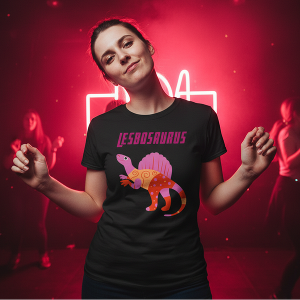 Lesbosaurus T-Shirt: soft cotton, bold “LESBOSAURUS” and a rainbow dino graphic, worn by a queer woman in pink neon-lit club.