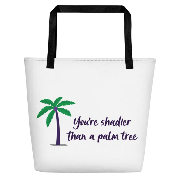 White tote bag with black handles, palm tree graphic, and “You’re shadier than a palm tree” text