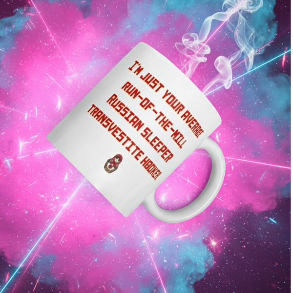 White ceramic mug featuring bold red lettering: “I’m Just Your Average Run-of-the-Mill Russian Sleeper Transvestite Hooker” with a Matryoshka doll graphic, embodying bold queer self-expression and pride.