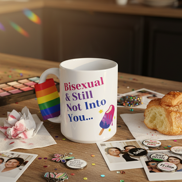 Bisexual & Still Not Into You Mug with prideful slogan and dripping popsicle illustration, surrounded by vibrant LGBTQ+ themed items like rainbow band, badges, and confetti on a casual, crafty tabletop.