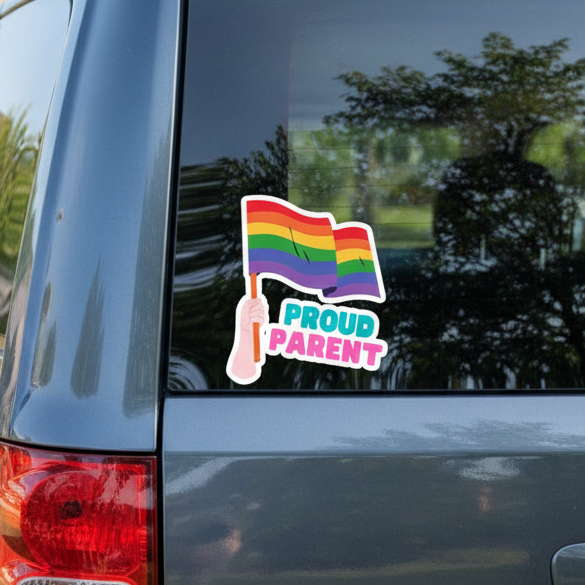 Proud Parent bubble-free sticker showing a hand waving a rainbow pride flag above bold “PROUD PARENT” text, on a car window.