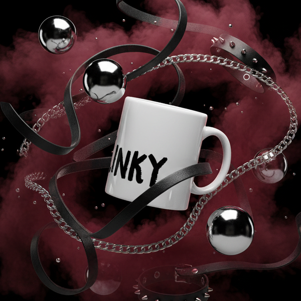 Close-up of a white mug marked “INKY,” surrounded by black straps, chains, and metal balls