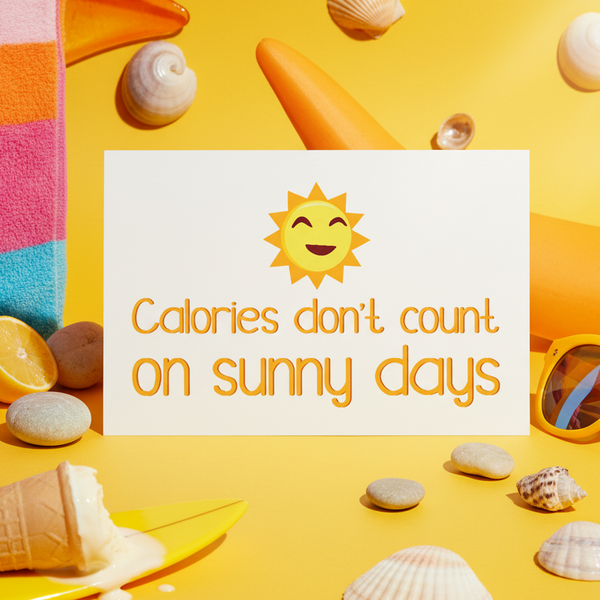 Postcard reading “Calories don’t count on sunny days,” styled with a smiling sun and beach objects