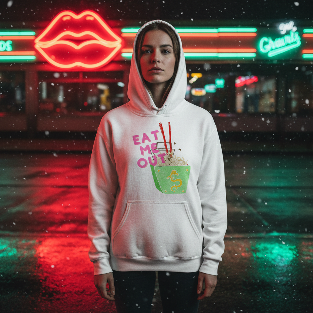 White hoodie with pink “EAT ME OUT” graphic and bowl illustration, worn in a snowy neon-lit street