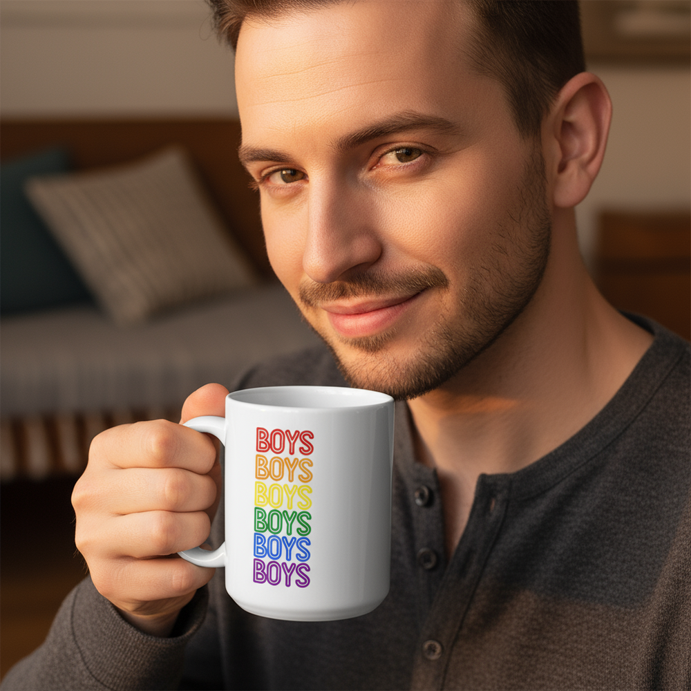 Hand holding a white mug printed with repeated rainbow-colored “BOYS” text