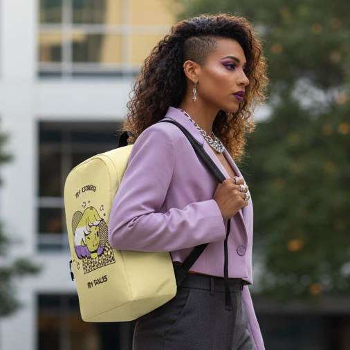 My Gender My Rules yellow backpack with a cartoon cat, carried by a queer femme in lavender blazer, gray pants