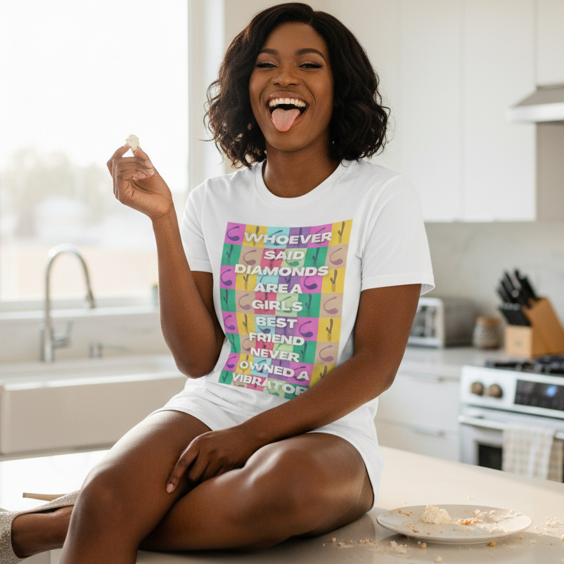 Smiling person in a white graphic T-shirt sits on a kitchen counter holding a pastry bite