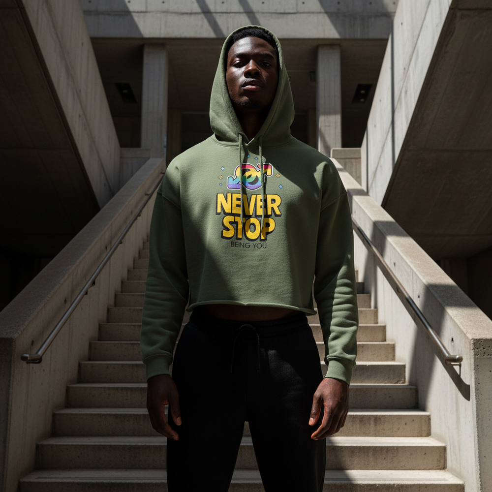Model wearing an olive cropped hoodie with colorful “NEVER STOP BEING YOU” graphic