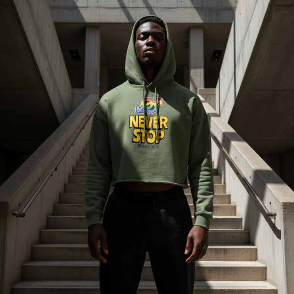 Model wearing an olive cropped hoodie with colorful “NEVER STOP BEING YOU” graphic