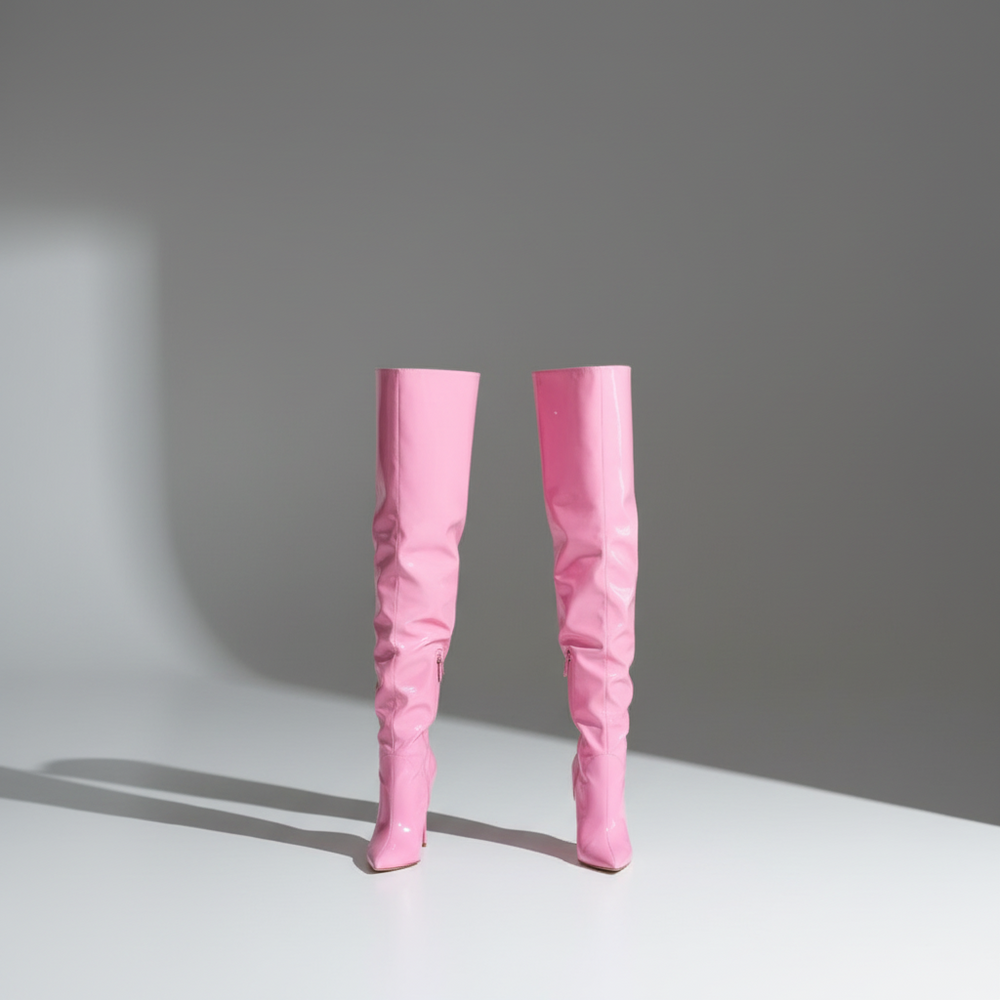 Pink stiletto boots with a glossy finish and pointed toes slay on a white surface