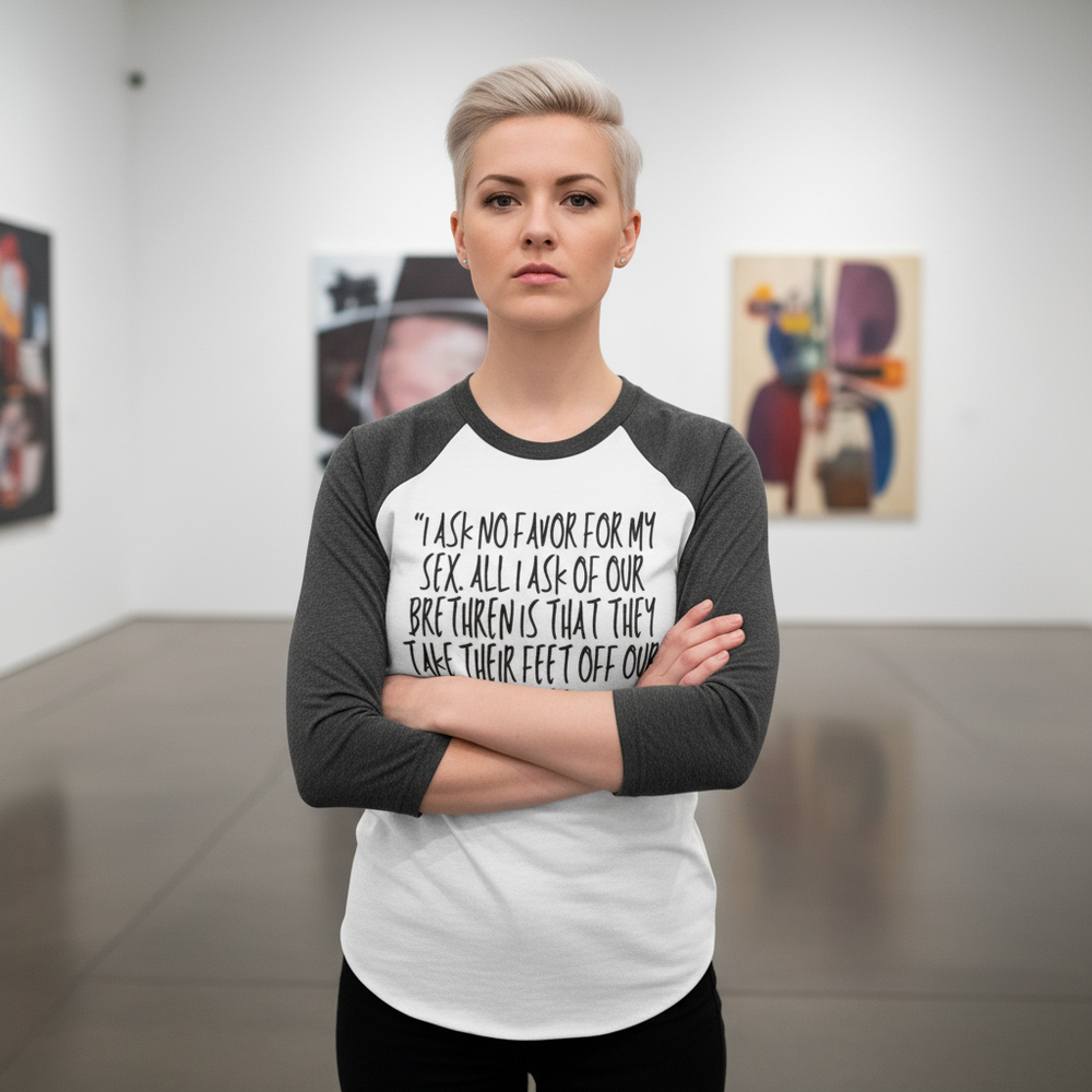 3/4 sleeve raglan shirt with “No Favor For My Sex” slogan, worn by a person with short blond hair in a bright art gallery.