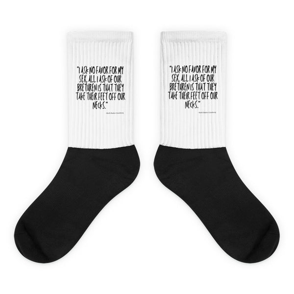 Pair of black crew socks with white cuffs reading “I ask no favor for my sex”