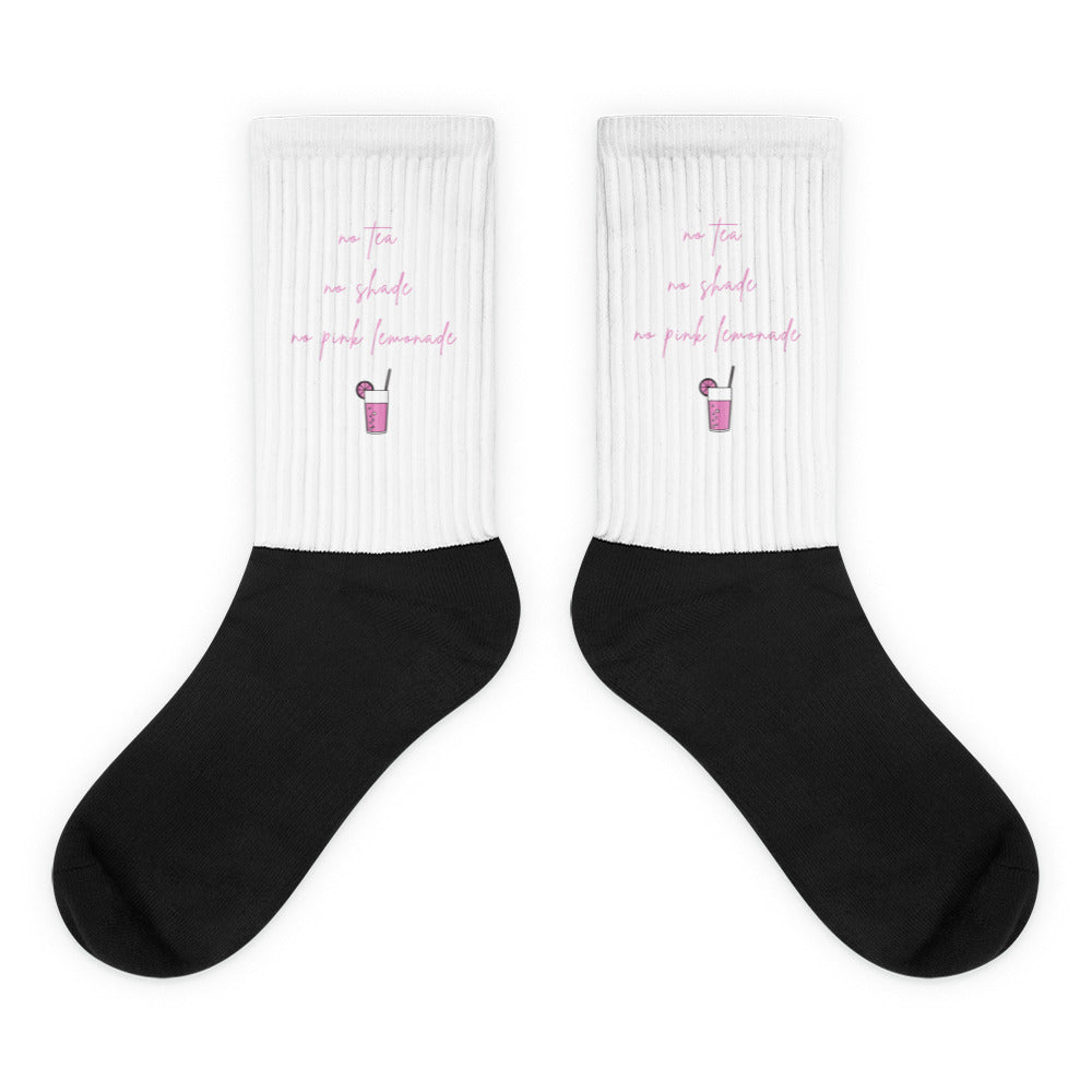 Pair of black socks with white cuffs reading “no tea, no shade, no pink lemonade”
