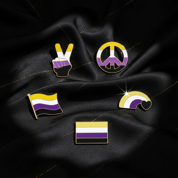 Five gold-outlined nonbinary pride enamel pins arranged on black fabric