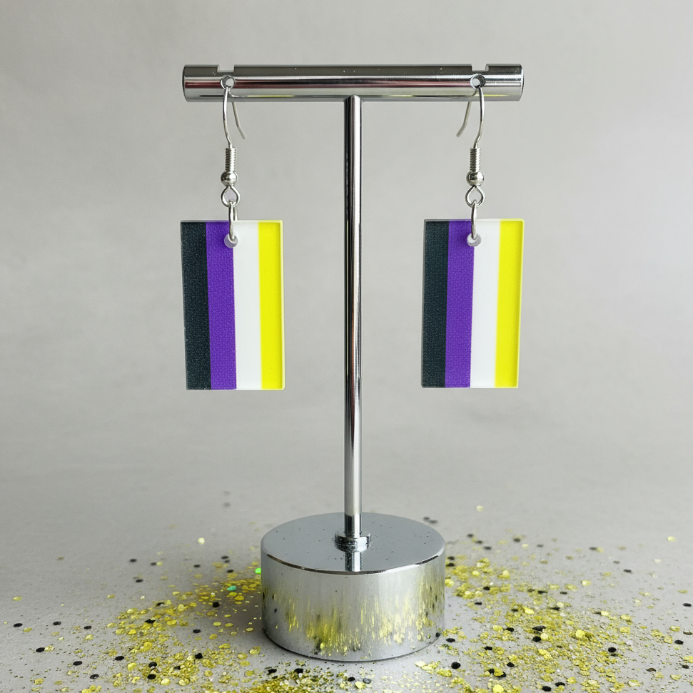 Pair of rectangular black, purple, white, and yellow dangle earrings on a silver stand