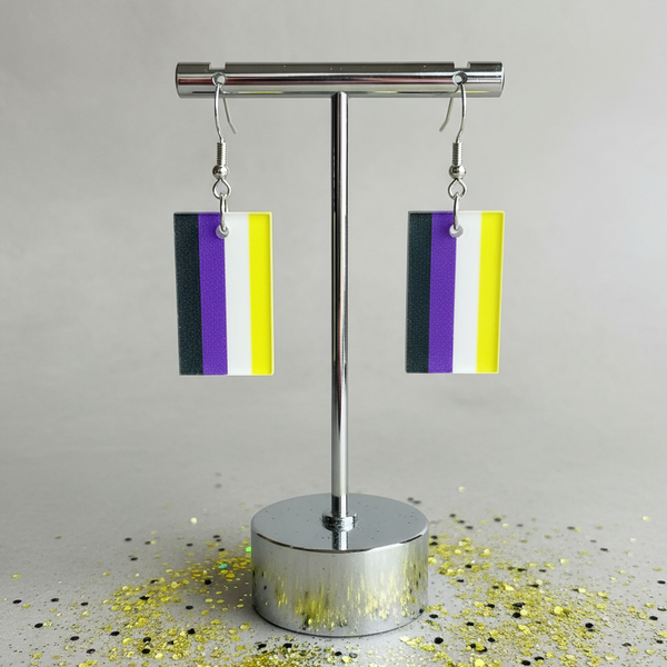 Pair of rectangular black, purple, white, and yellow dangle earrings on a silver stand