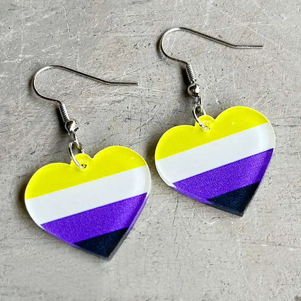 Pair of nonbinary pride heart-shaped acrylic dangle earrings on a gray surface