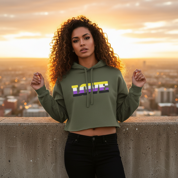 Non-Binary Love Crop Hoodie with “LOVE” in rainbow stripes, worn by a curly-haired person on a sunset rooftop