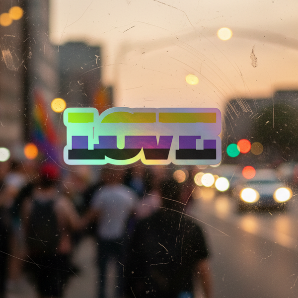 Non-Binary Love holographic sticker shines on a scratched window, with blurred city lights, people