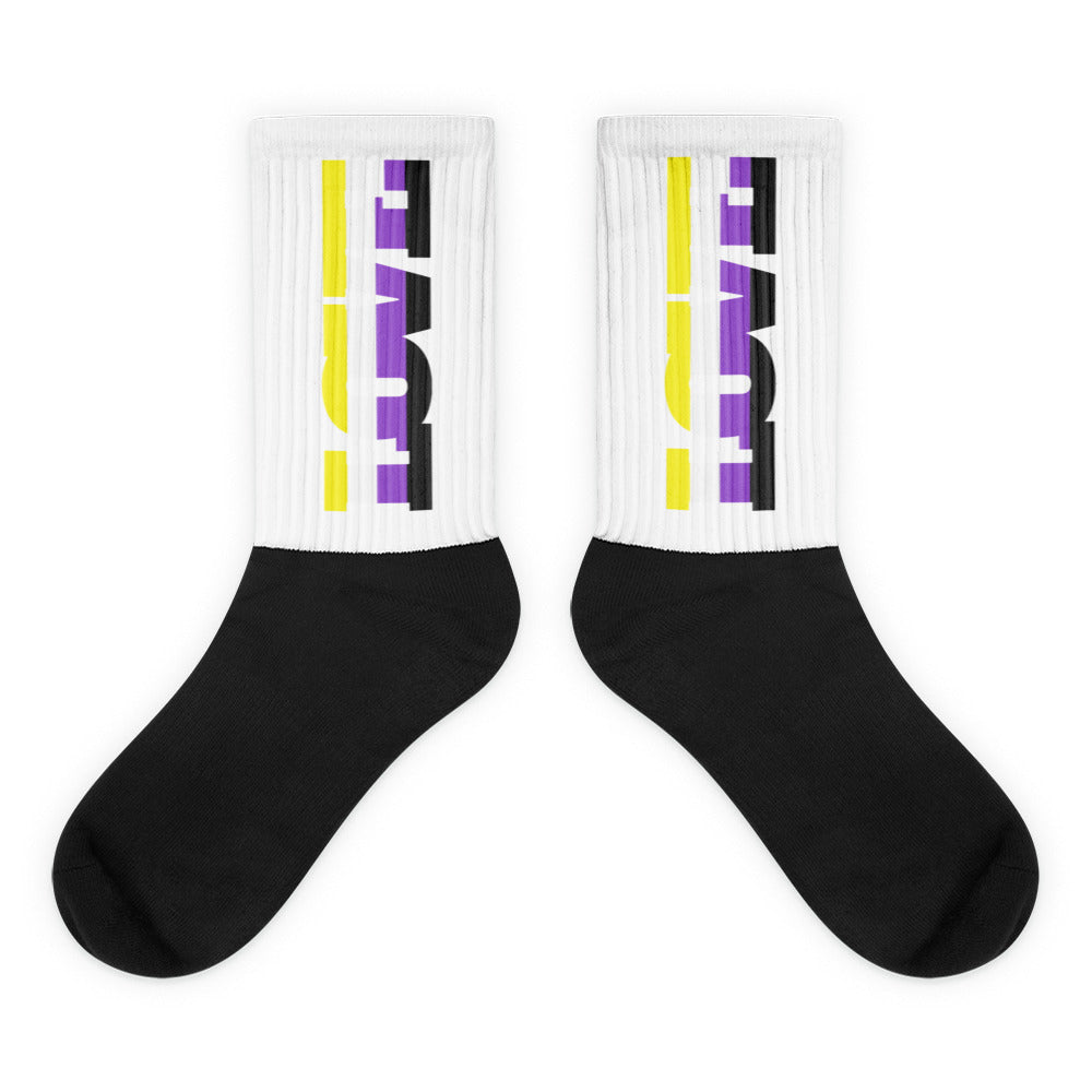 Pair of black socks with white ribbed cuffs and yellow, purple, and black graphics