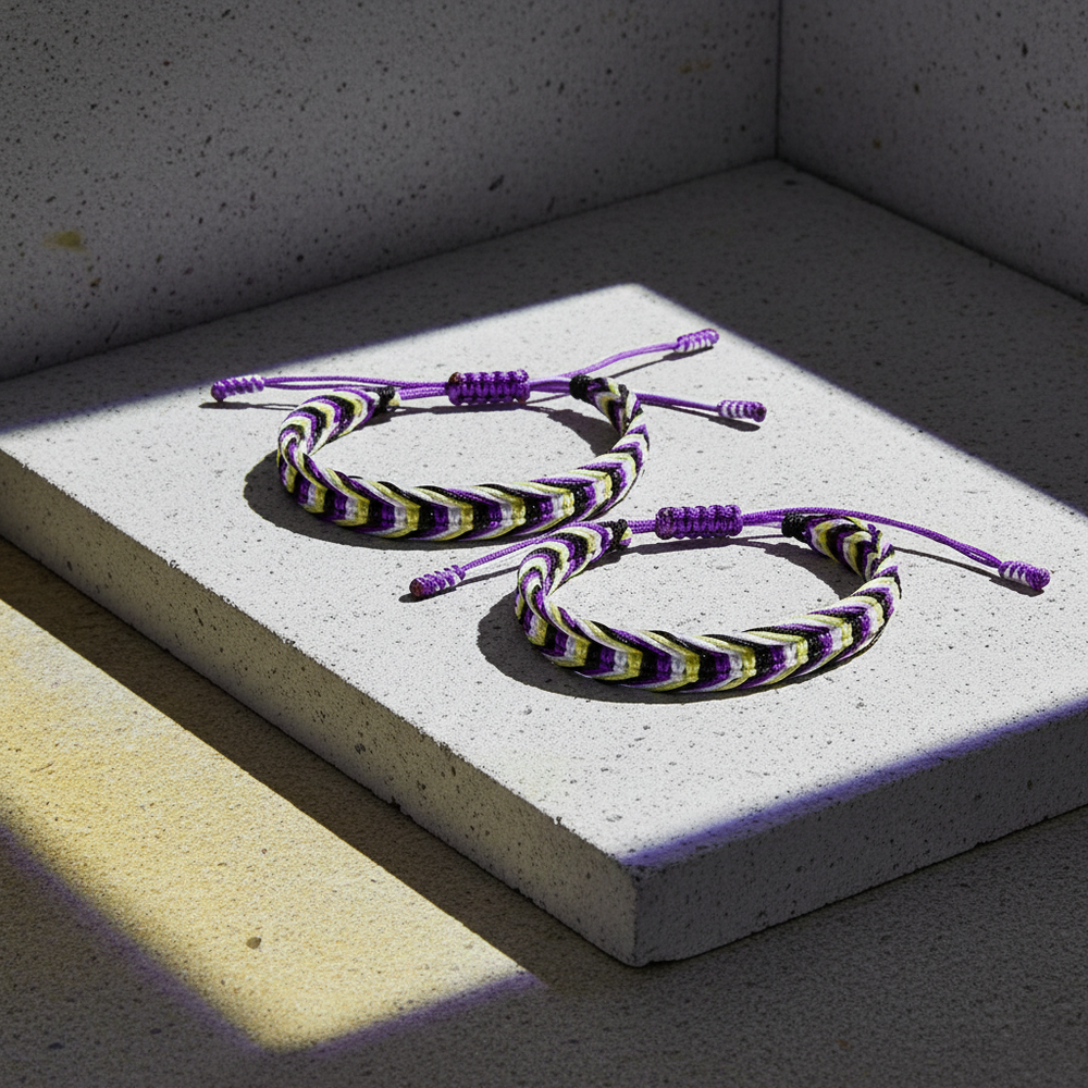 Two purple, black, white, and yellow braided bracelets on a concrete block