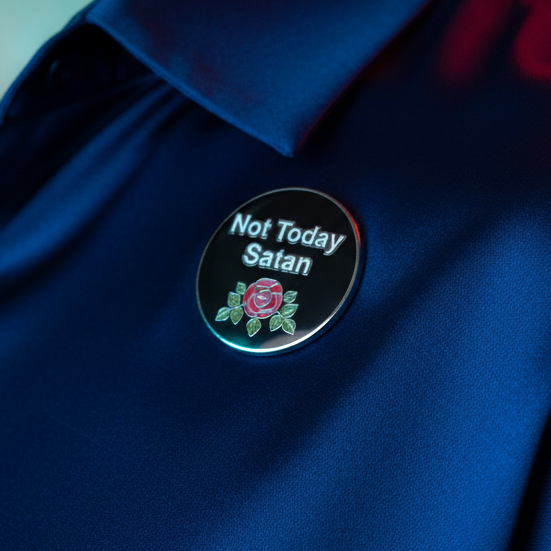 Close-up of a black enamel pin reading “Not Today Satan” with a rose design