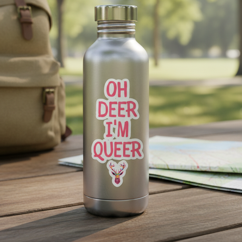 “Oh Deer Im Queer” bubble-free sticker with deer art on a silver water bottle; picnic table, postcards, beige backpack, map