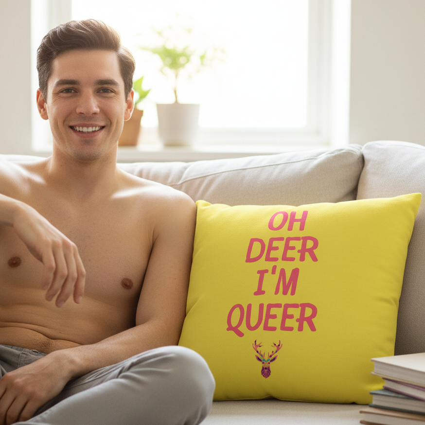 Yellow pillow reading “OH DEER I’M QUEER,” with a colorful deer head, beside a shirtless person on a couch