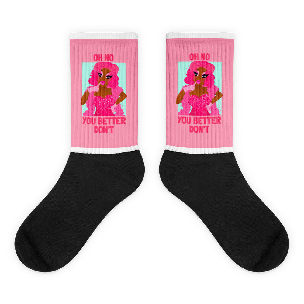 Pair of black crew socks with pink cuffs and drag queen graphic reading “OH NO YOU BETTER DON’T”