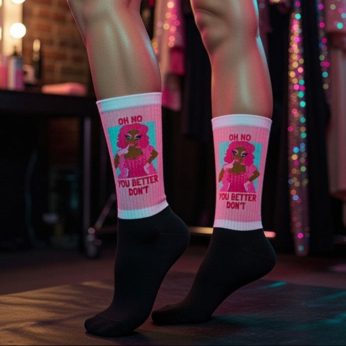 Oh No You Betta Don’t Socks—white crew socks with cushy bottoms, a cartoon drag queen, and “OH NO YOU BETTER DONT” slogan.
