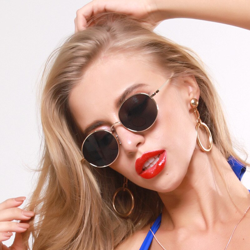 Close-up model wearing round black-lensed sunglasses with thin gold frames