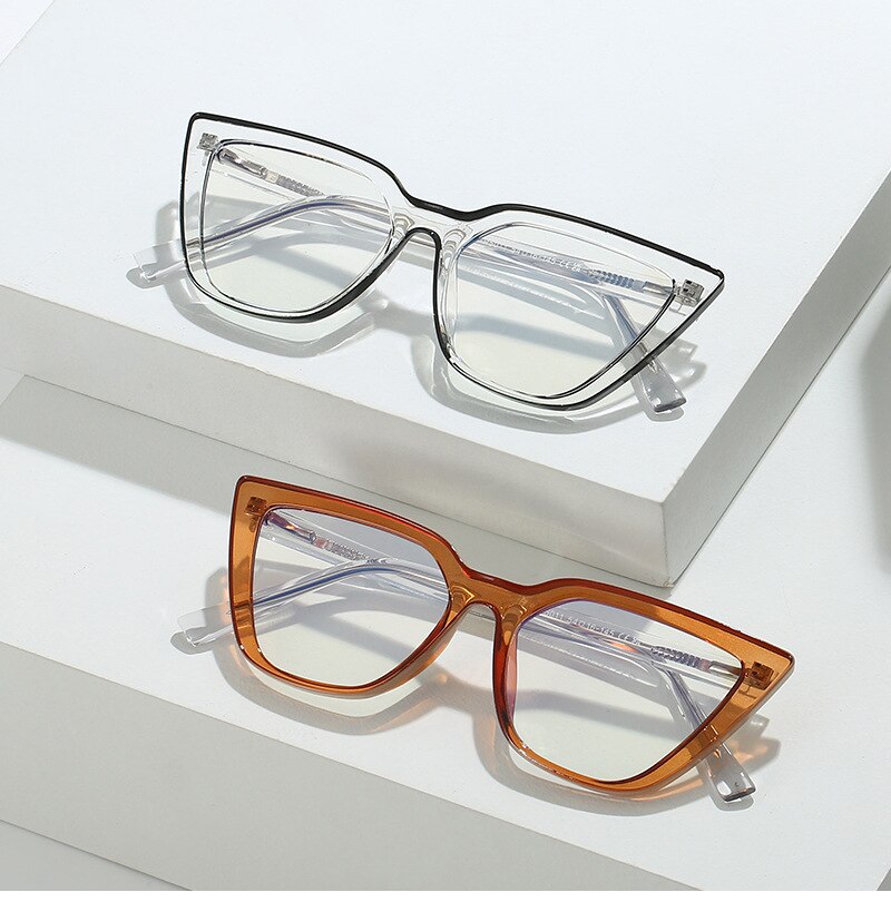 Two cat-eye glasses, one clear and one amber, displayed on white stepped blocks
