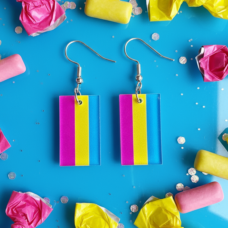 Pair of rectangular pink, yellow, and blue striped dangle earrings on a bright blue background