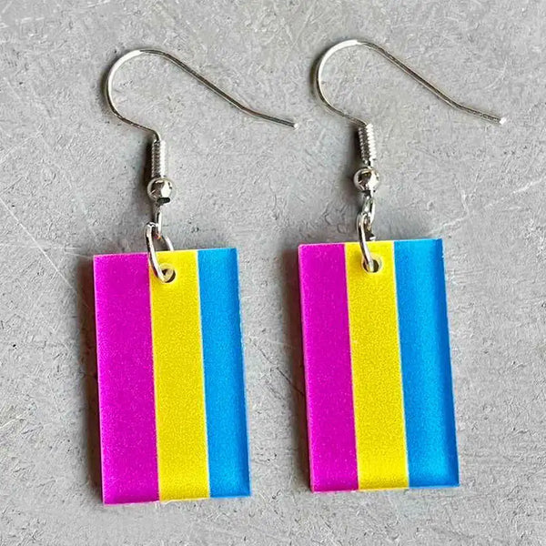 Pair of rectangular pink, yellow, and blue striped acrylic dangle earrings on a gray surface