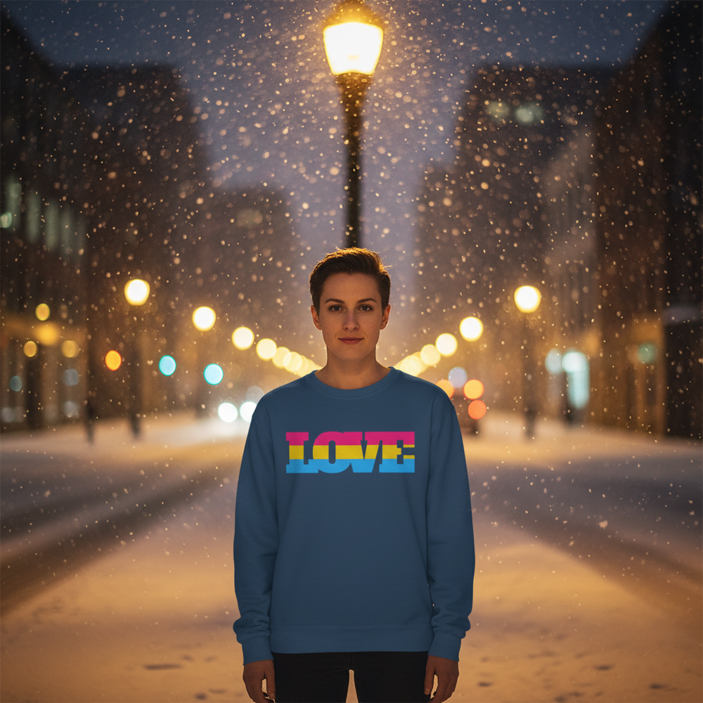 Person wearing a blue sweatshirt with multicolor LOVE lettering on a snowy city street at night