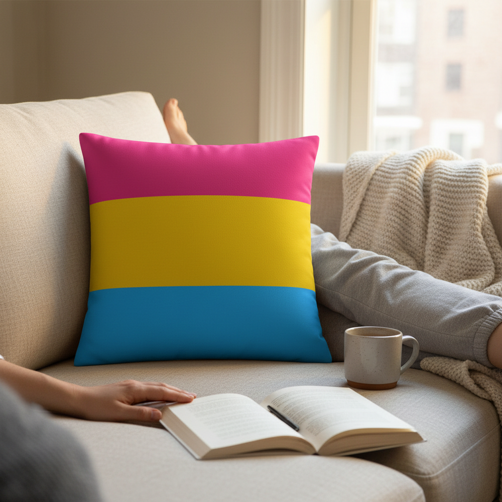 Pansexual Premium Pillow with bright pride colors sits by a mug as a person reads on a beige sofa