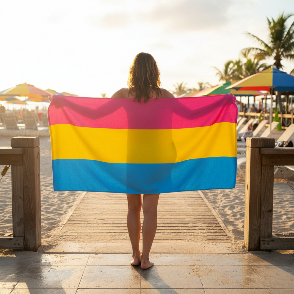 Pansexual Pride Flag towel with bold pink, yellow, and blue stripes held on a sunny beach boardwalk