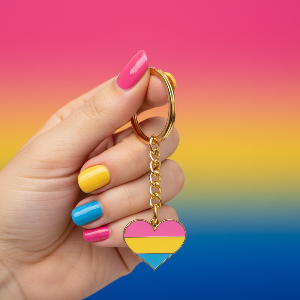 Hand holding a pansexual pride heart keychain with gold ring and chain
